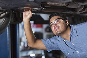 Mecánico trabajando debajo de un automóvil elevado.